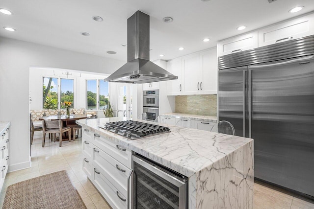 kitchen with white cabinets, island range hood, beverage cooler, stainless steel appliances, and a center island