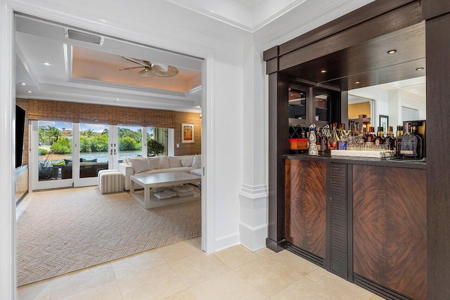 bar with ceiling fan, a raised ceiling, french doors, light carpet, and crown molding