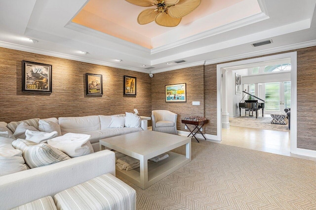 living room with ceiling fan, a raised ceiling, and crown molding