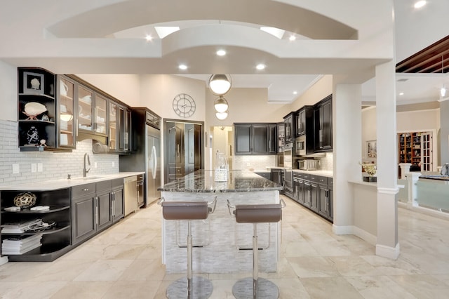 kitchen with dark stone counters, sink, a kitchen island, stainless steel appliances, and backsplash