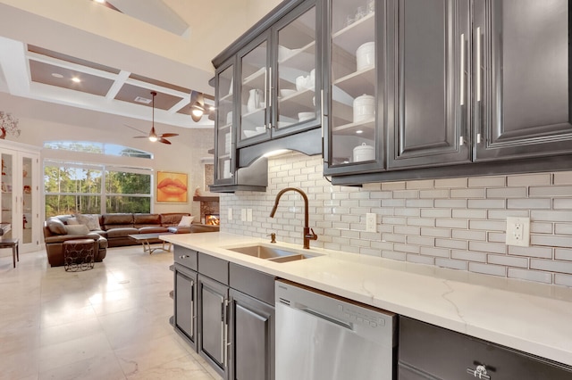 kitchen with decorative backsplash, coffered ceiling, light stone countertops, dishwasher, and sink