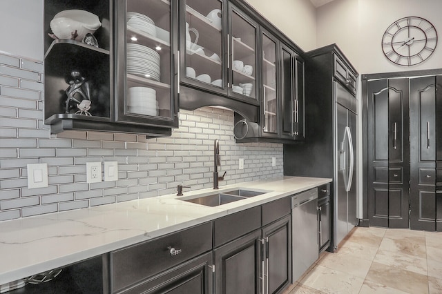 kitchen with light stone counters, appliances with stainless steel finishes, tasteful backsplash, and sink