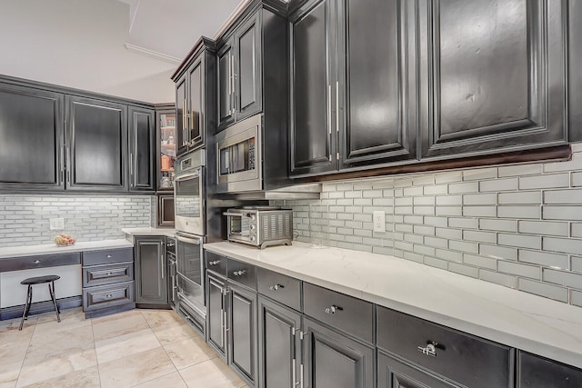 kitchen featuring light stone counters, appliances with stainless steel finishes, and tasteful backsplash