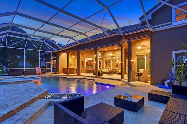 pool at dusk featuring a lanai, an outdoor living space, an in ground hot tub, and a patio area