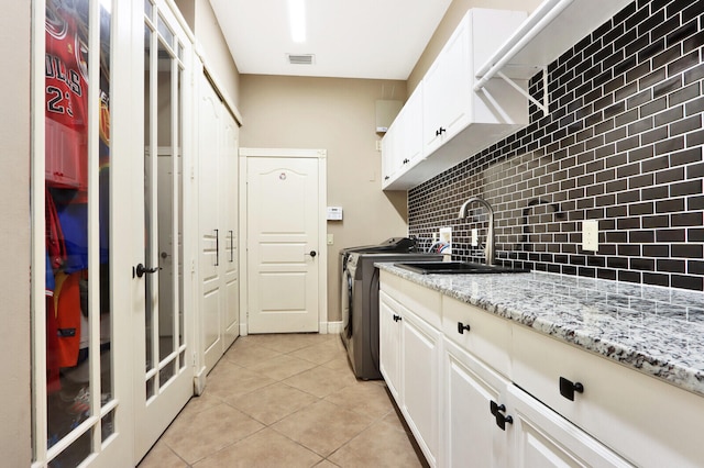 clothes washing area with light tile patterned floors, cabinets, sink, and washer / dryer