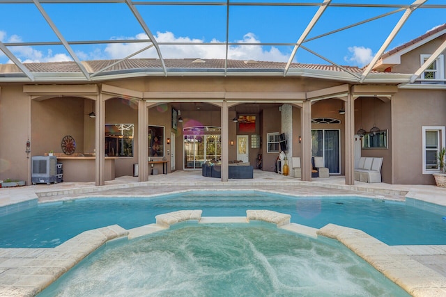 view of pool featuring glass enclosure, an in ground hot tub, ceiling fan, and a patio