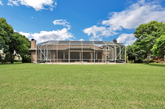 back of house with glass enclosure and a lawn