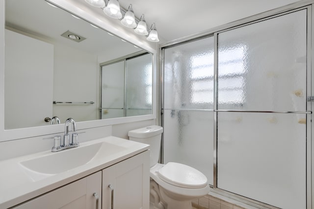 bathroom with vanity, a shower with shower door, toilet, and tile patterned floors