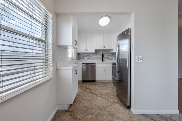 kitchen with appliances with stainless steel finishes, decorative backsplash, white cabinetry, light tile patterned floors, and sink