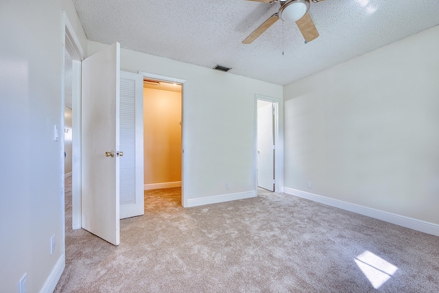 unfurnished bedroom featuring ceiling fan, a textured ceiling, light carpet, and a closet