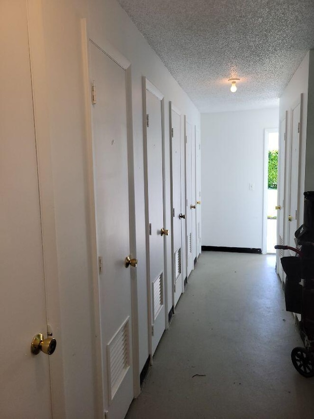 hallway with concrete flooring and a textured ceiling