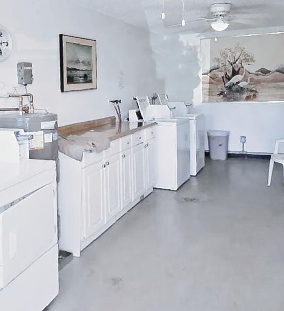 laundry room with water heater, cabinets, ceiling fan, and independent washer and dryer