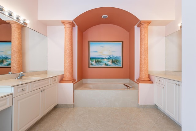 full bathroom with tile patterned flooring, vanity, baseboards, ornate columns, and a garden tub