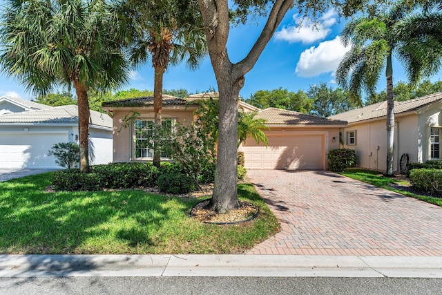 single story home featuring a tiled roof, decorative driveway, a front yard, an attached garage, and stucco siding