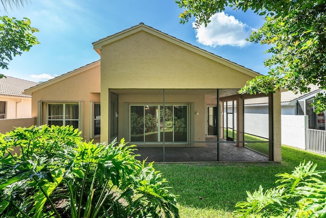 rear view of property featuring a patio area, a yard, stucco siding, and fence