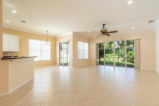 unfurnished living room featuring ornamental molding, ceiling fan, baseboards, and visible vents