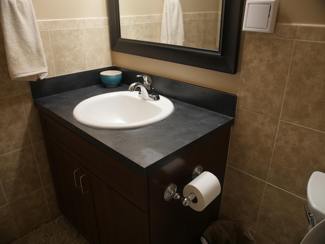 bathroom with tile walls, vanity, and toilet