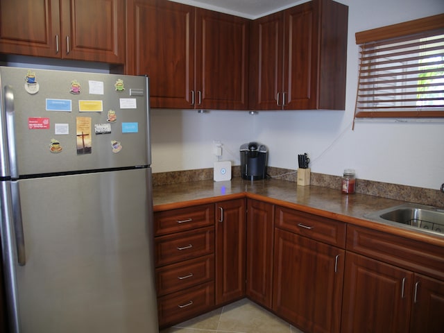 kitchen with stainless steel fridge, sink, and light tile patterned floors