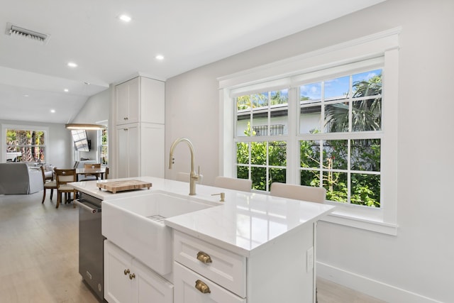 kitchen featuring a center island with sink, white cabinets, vaulted ceiling, and sink