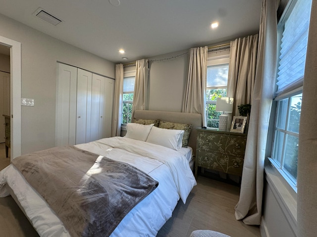 bedroom with multiple windows, a closet, and hardwood / wood-style flooring