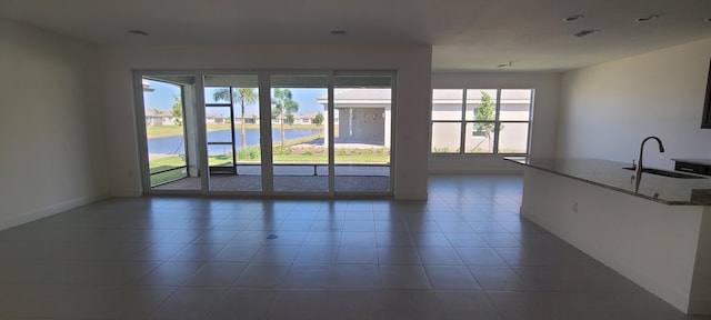 spare room featuring sink, tile patterned floors, and a water view