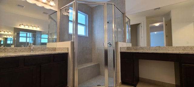 bathroom with a shower with door, vanity, and tile patterned floors