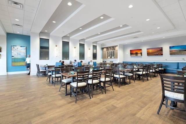 dining area featuring light hardwood / wood-style floors and a raised ceiling