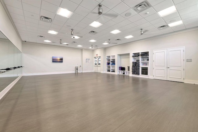 interior space featuring a paneled ceiling, baseboards, wood finished floors, and visible vents