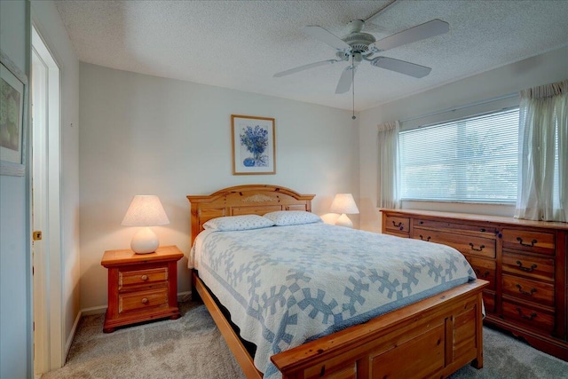 bedroom with ceiling fan, baseboards, a textured ceiling, and light colored carpet