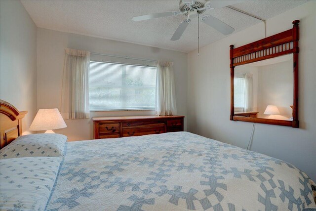 bedroom with a ceiling fan and a textured ceiling