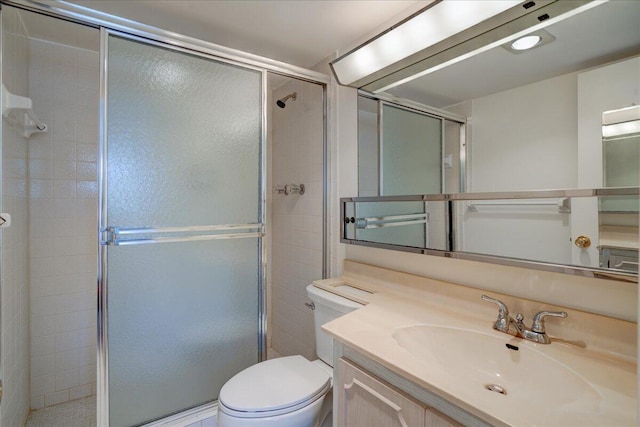 bathroom featuring toilet, a shower stall, and vanity