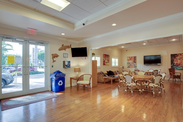 interior space featuring a tray ceiling, french doors, light wood-style flooring, and crown molding