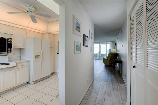 hall with a textured ceiling, light wood-type flooring, and baseboards