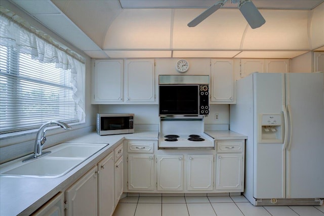 kitchen featuring white appliances, light countertops, a sink, and white cabinetry