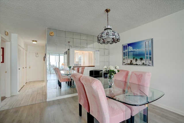 dining area featuring light wood-style flooring and a textured ceiling