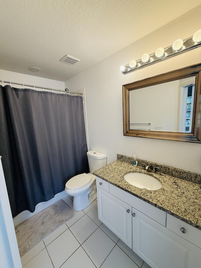 bathroom with vanity, toilet, tile patterned flooring, and a textured ceiling