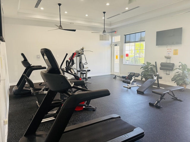 exercise room featuring a raised ceiling and ornamental molding