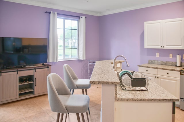 kitchen featuring a center island with sink, ornamental molding, and white cabinetry