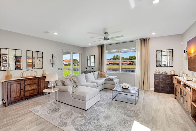 living room featuring a wealth of natural light, ceiling fan, and light wood-type flooring