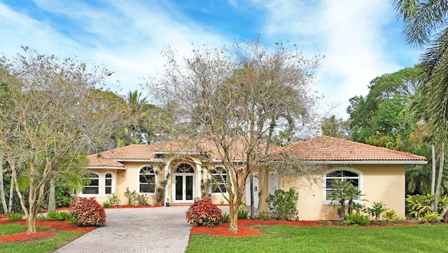 mediterranean / spanish house featuring french doors and a front lawn