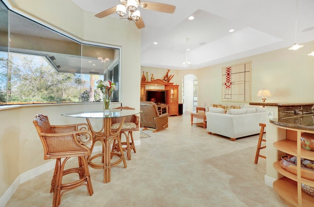 dining space featuring ceiling fan, a raised ceiling, and light tile patterned floors