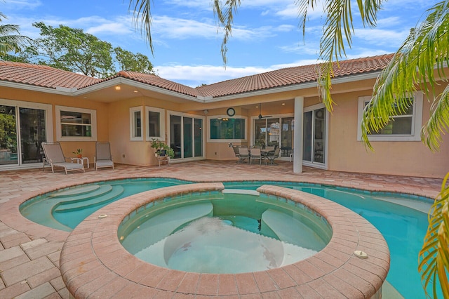 rear view of property featuring a swimming pool with hot tub and a patio area