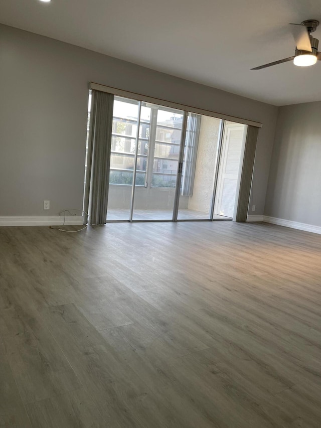 spare room featuring baseboards, ceiling fan, and wood finished floors