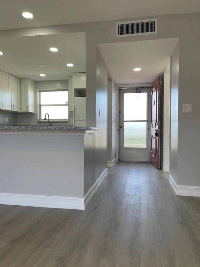 kitchen with white refrigerator, light stone countertops, dark wood-type flooring, and white cabinetry