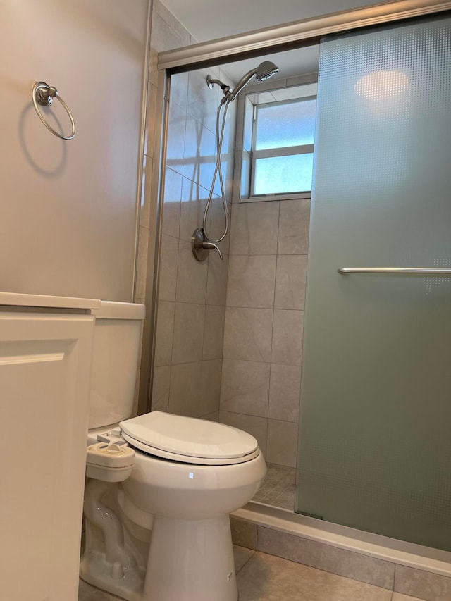 bathroom featuring a shower with shower door, toilet, and tile patterned floors