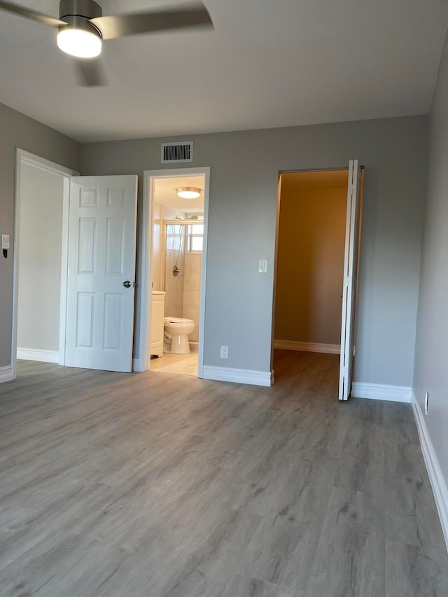 unfurnished bedroom featuring ensuite bath, ceiling fan, and light hardwood / wood-style flooring