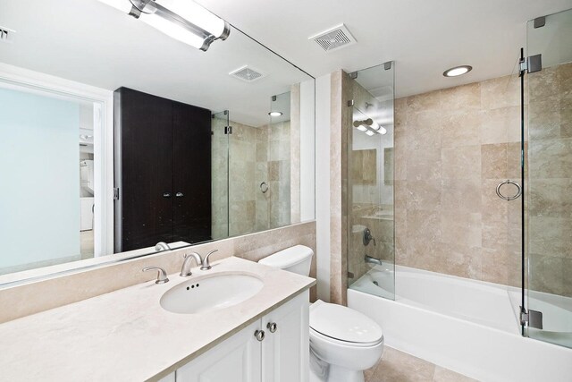 full bathroom featuring shower / bath combination with glass door, tile patterned flooring, vanity, and toilet