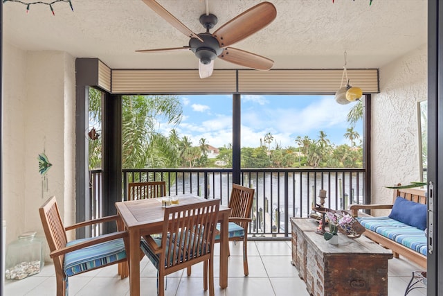 sunroom / solarium with a water view and ceiling fan