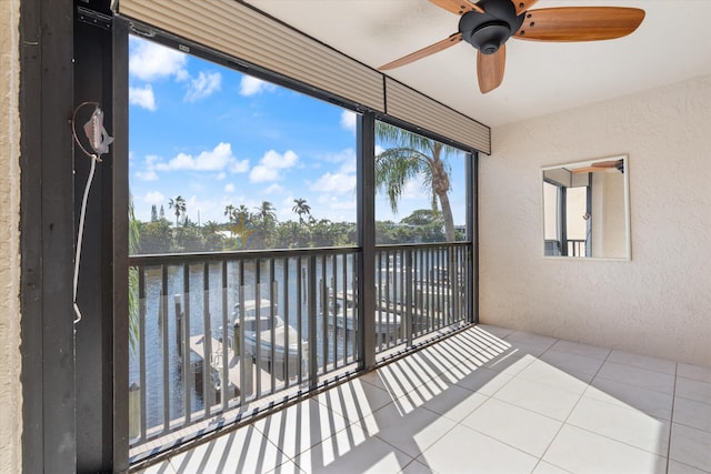 unfurnished sunroom with ceiling fan and a water view