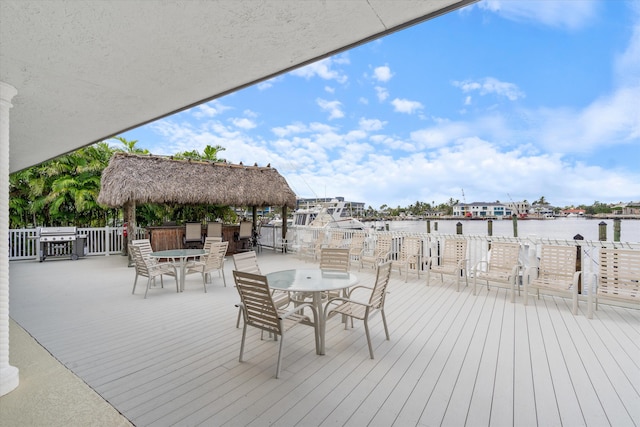 wooden terrace with a gazebo, a grill, and a water view